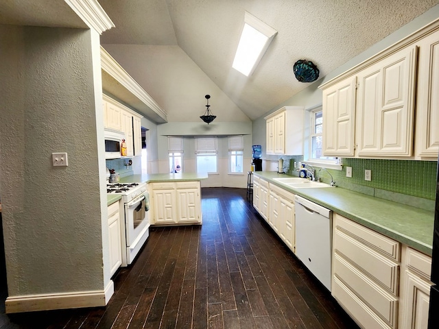 kitchen featuring dark wood-style floors, backsplash, a sink, white appliances, and a peninsula