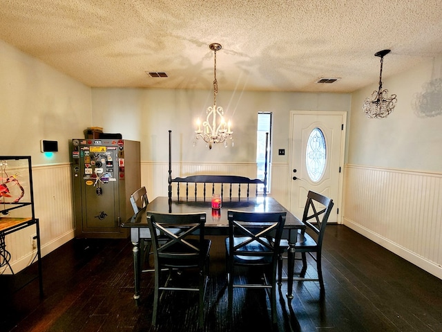 dining space with dark wood-style floors, a wainscoted wall, visible vents, and a textured ceiling