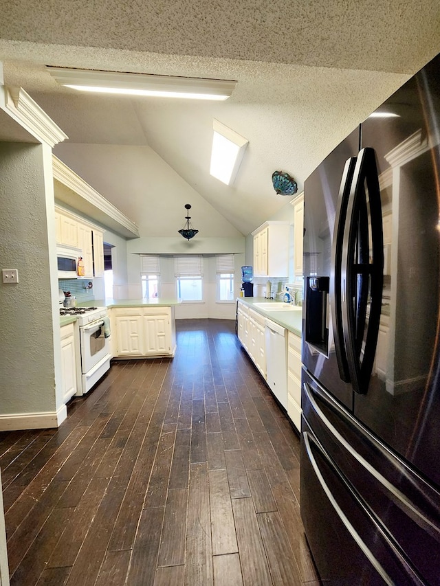 kitchen featuring white appliances, dark wood-type flooring, a peninsula, vaulted ceiling, and light countertops