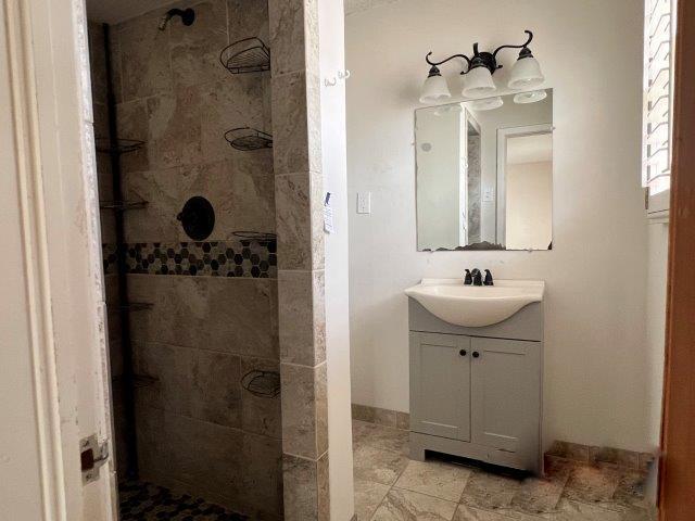 bathroom featuring a tile shower and vanity