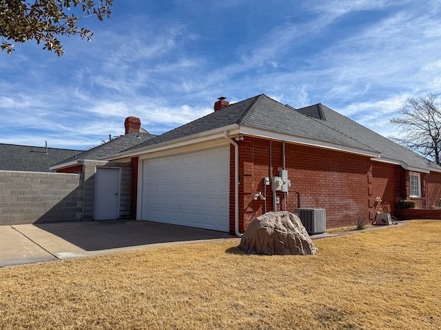 view of home's exterior featuring a garage, cooling unit, and a lawn