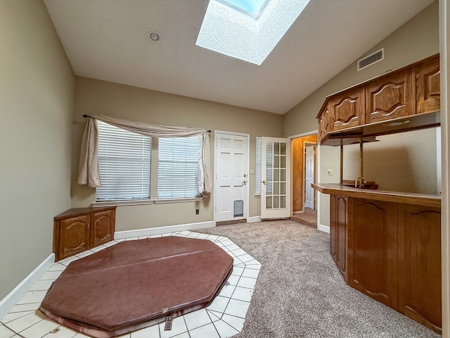 kitchen with light carpet and vaulted ceiling with skylight