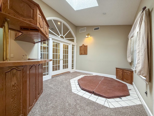 interior space featuring light carpet, sink, french doors, and vaulted ceiling with skylight