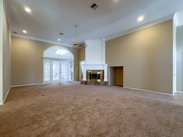 unfurnished living room featuring ornamental molding, a large fireplace, light colored carpet, and french doors