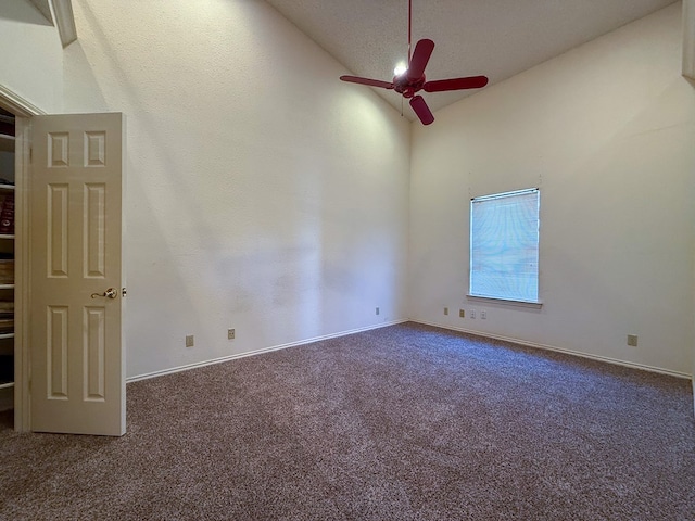 carpeted empty room featuring high vaulted ceiling and ceiling fan