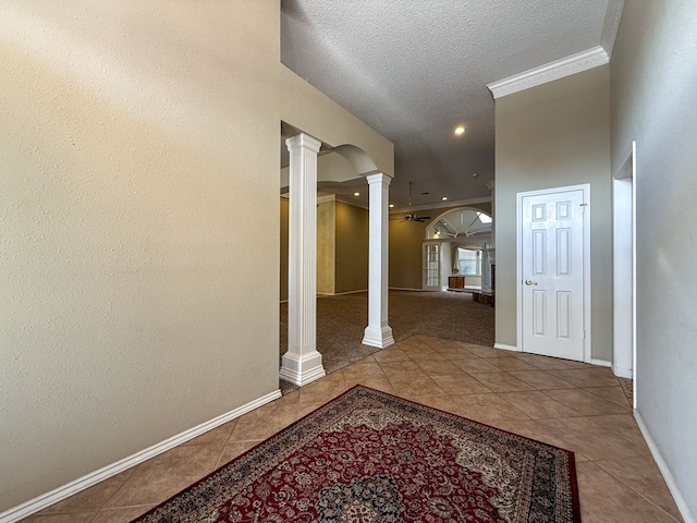 hall featuring crown molding, tile patterned floors, decorative columns, and a textured ceiling