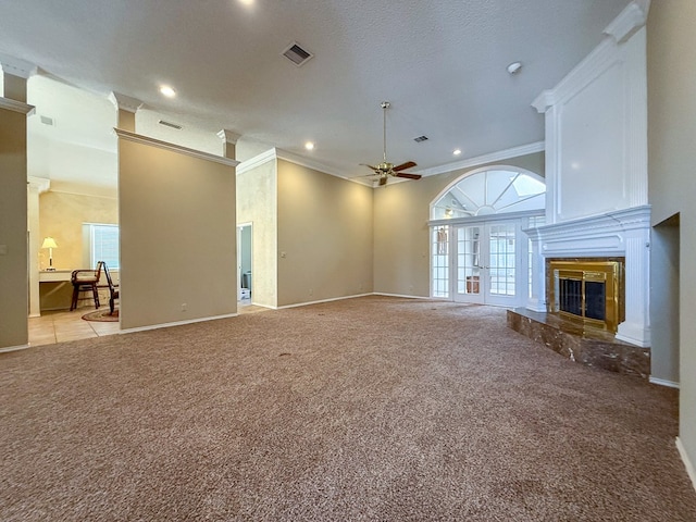 unfurnished living room with crown molding, ceiling fan, a large fireplace, light carpet, and french doors