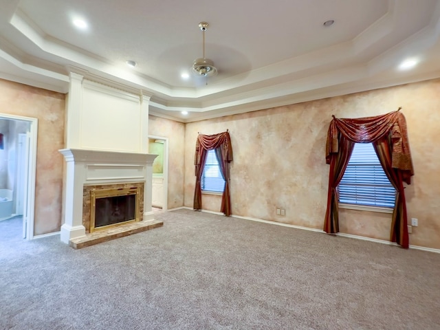 unfurnished living room featuring a raised ceiling, crown molding, and carpet flooring