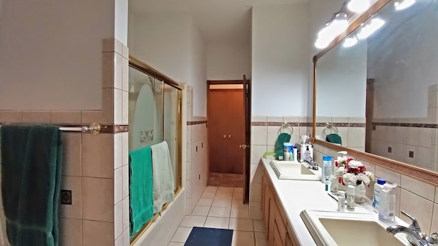 full bath with a wainscoted wall, tile walls, a sink, and tile patterned floors