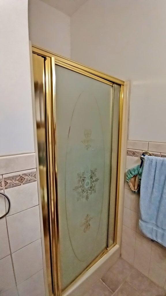 bathroom featuring tile patterned flooring, wainscoting, a shower stall, and tile walls