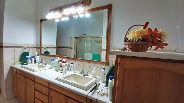 bathroom with a sink, a shower stall, and double vanity