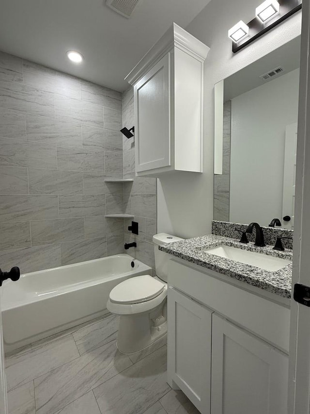 full bathroom featuring vanity, tiled shower / bath combo, and toilet