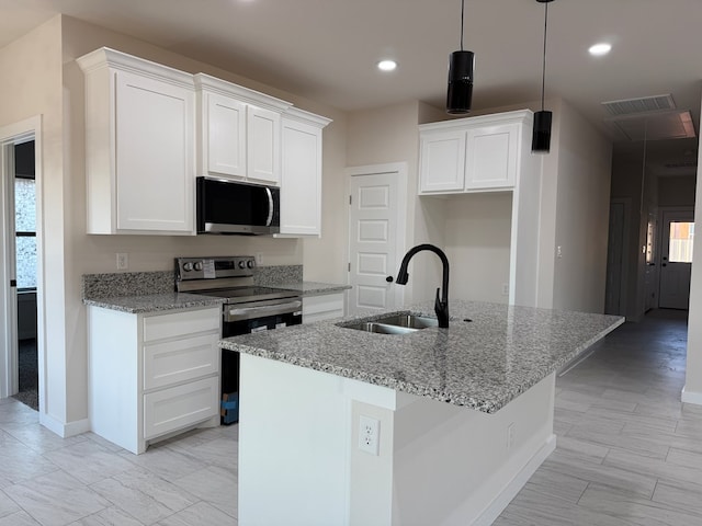 kitchen with sink, stainless steel appliances, white cabinets, and a center island with sink