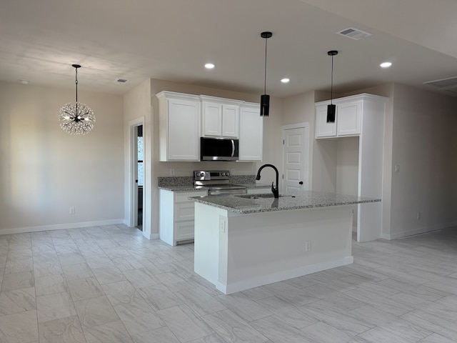 kitchen with stainless steel appliances, a kitchen island with sink, white cabinets, and light stone counters