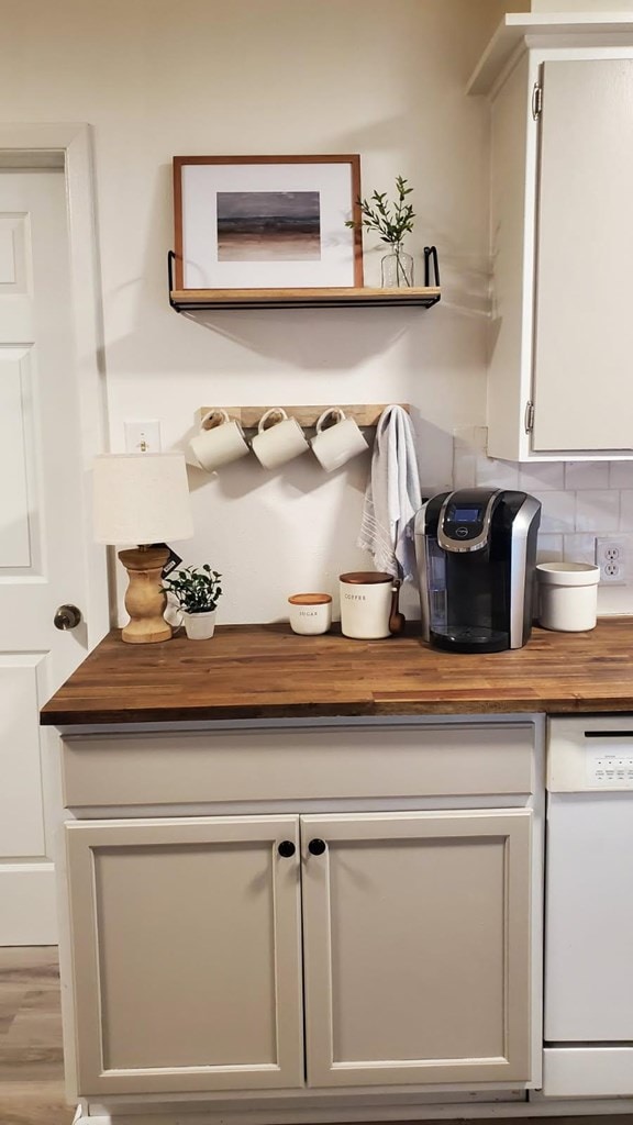 bar featuring tasteful backsplash, white cabinetry, white dishwasher, and light hardwood / wood-style flooring