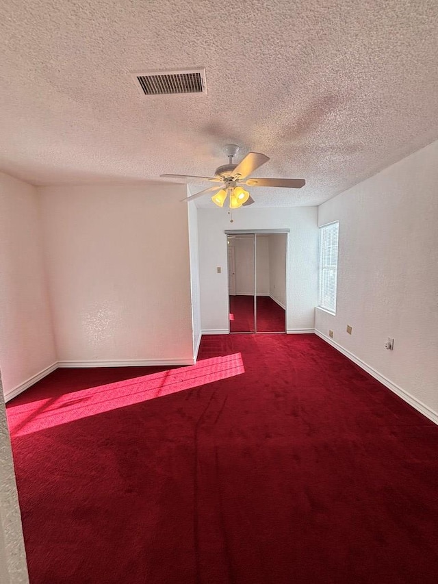 spare room with a textured ceiling, carpet floors, and ceiling fan