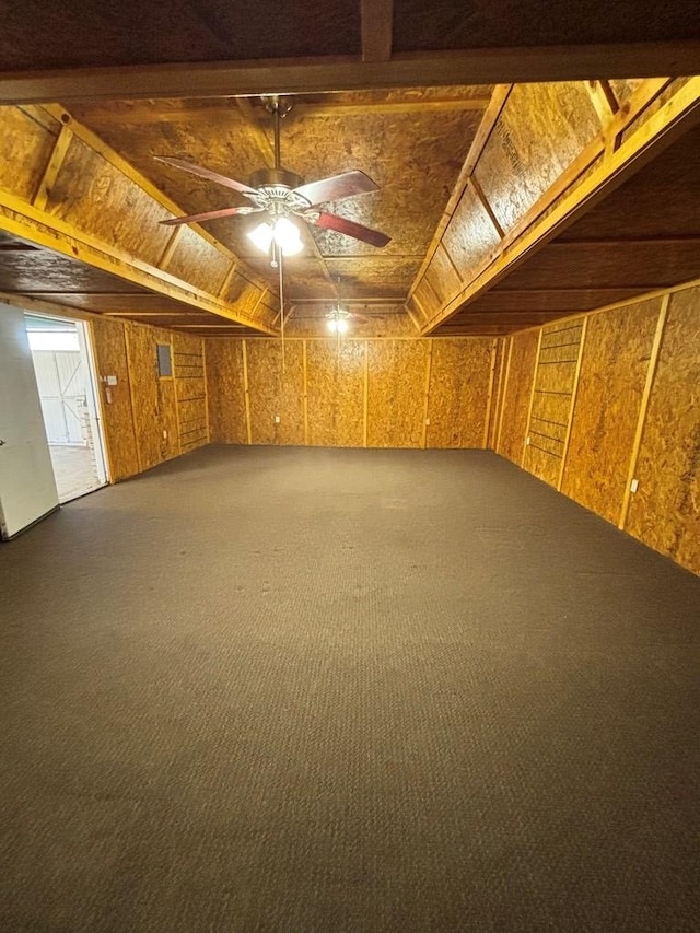 interior space with carpet flooring, ceiling fan, lofted ceiling, and wood walls