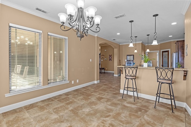 kitchen with a kitchen bar, light stone counters, crown molding, decorative light fixtures, and stainless steel refrigerator