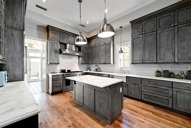 kitchen featuring light wood-type flooring, high end stainless steel range oven, extractor fan, a kitchen island, and hanging light fixtures