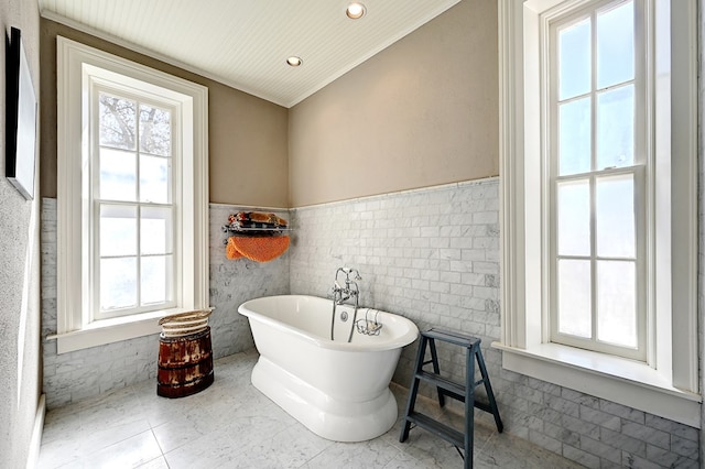 bathroom featuring tile patterned flooring, a bath, tile walls, and ornamental molding