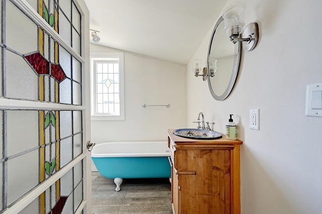 bathroom with a bathing tub, vanity, hardwood / wood-style flooring, and lofted ceiling