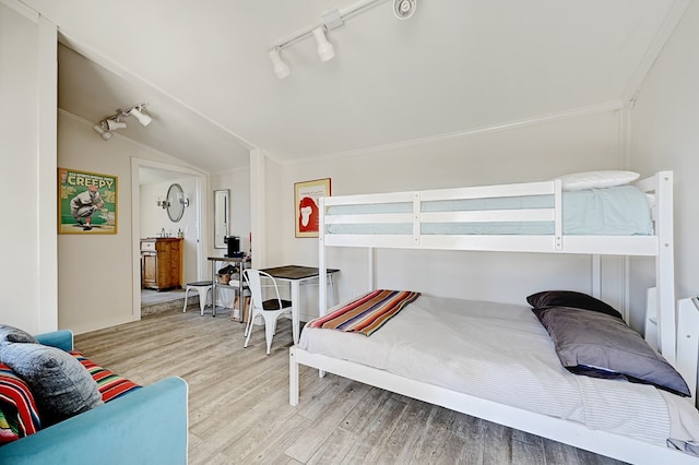 bedroom with ornamental molding, rail lighting, light hardwood / wood-style flooring, and lofted ceiling