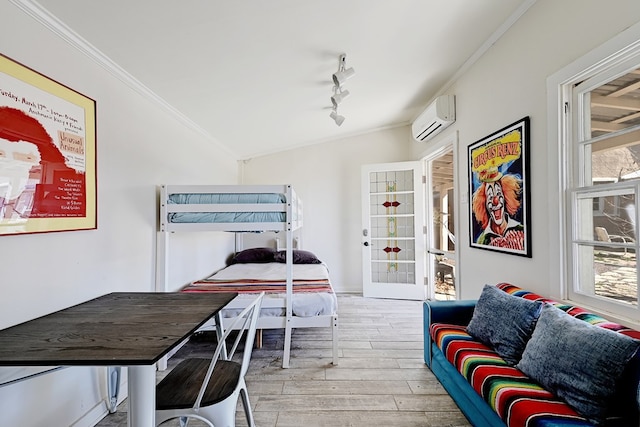 bedroom featuring a wall mounted air conditioner, rail lighting, crown molding, light hardwood / wood-style floors, and lofted ceiling