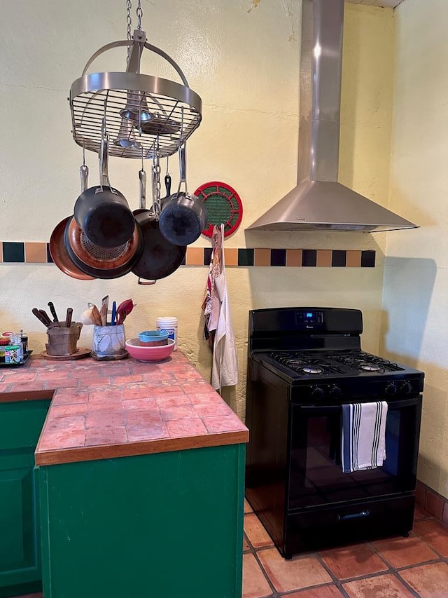 kitchen featuring island exhaust hood, tile counters, black gas stove, and green cabinetry