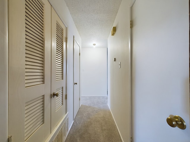 corridor featuring a textured ceiling and light carpet