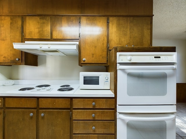 kitchen featuring tile patterned flooring, a textured ceiling, and white appliances