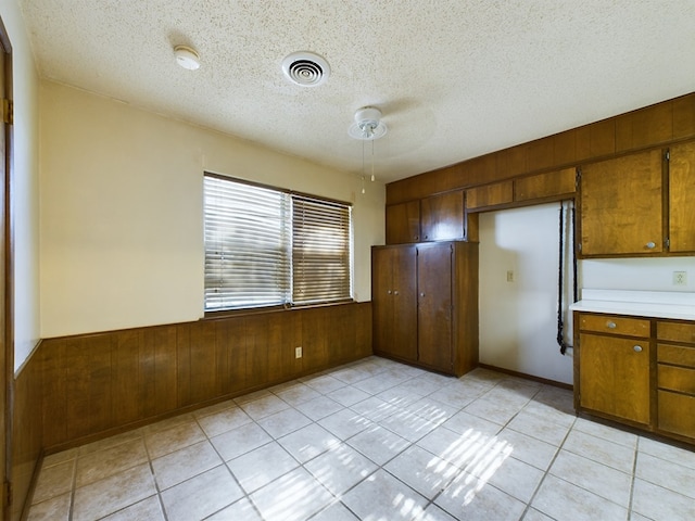 kitchen featuring light tile patterned floors, a textured ceiling, and wood walls