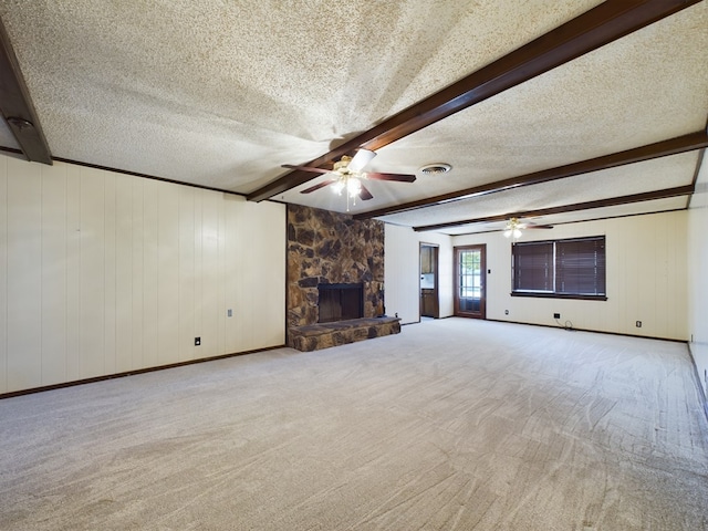 unfurnished living room with light carpet, a fireplace, beamed ceiling, and a textured ceiling