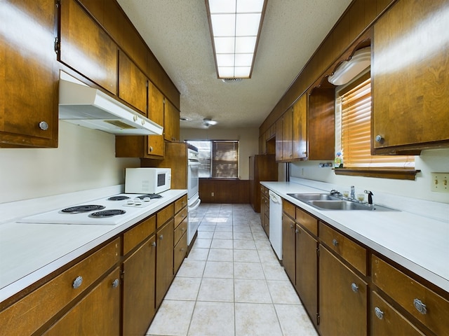 kitchen featuring light tile patterned floors, white appliances, a textured ceiling, and sink