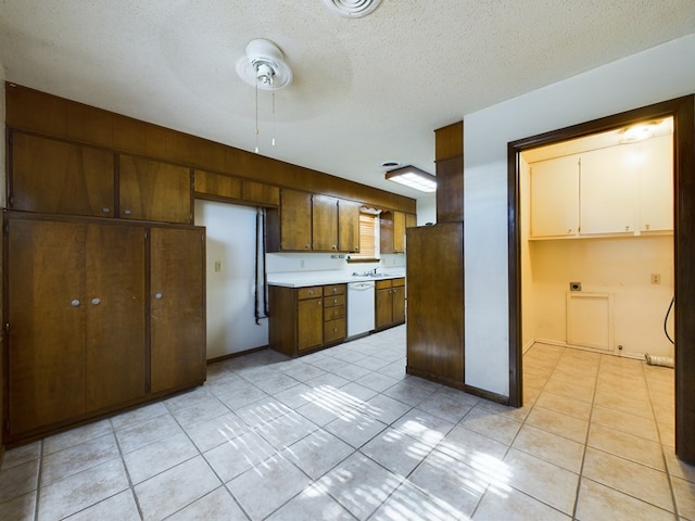 kitchen with ceiling fan, dishwasher, sink, a textured ceiling, and light tile patterned floors