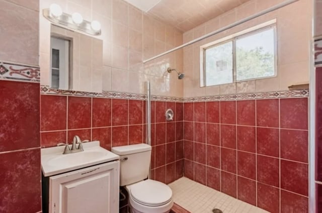 full bath featuring tile walls, toilet, tiled shower, and vanity