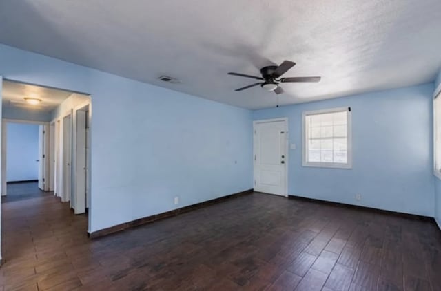 unfurnished room with visible vents, baseboards, dark wood-type flooring, and a ceiling fan