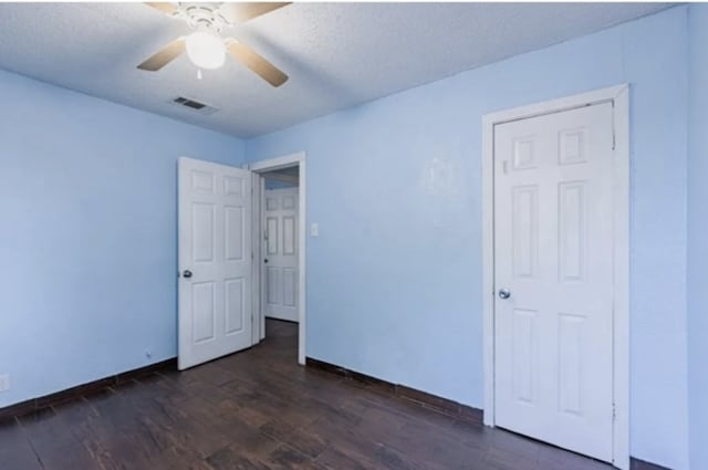 unfurnished bedroom featuring visible vents, dark wood-type flooring, a ceiling fan, a textured ceiling, and baseboards