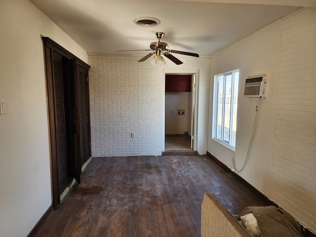 unfurnished bedroom with ceiling fan, dark wood-type flooring, and brick wall