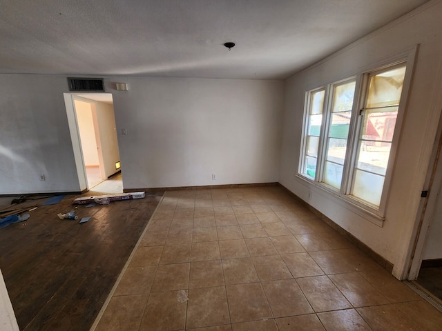 tiled empty room with a textured ceiling