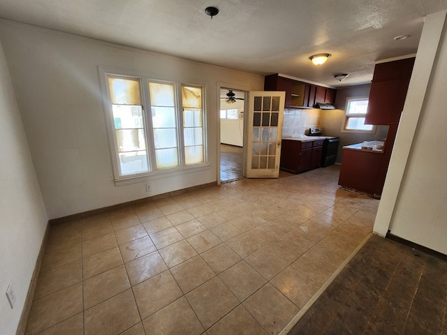 kitchen with ceiling fan, range with electric stovetop, light tile patterned floors, and a textured ceiling