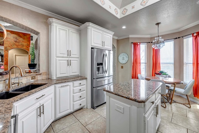 kitchen with a sink, a wealth of natural light, ornamental molding, and stainless steel refrigerator with ice dispenser