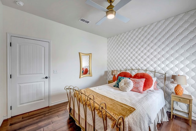 bedroom featuring visible vents, baseboards, a ceiling fan, and wood finished floors