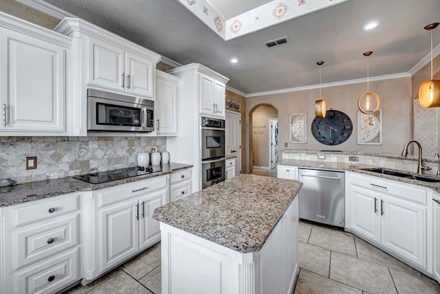 kitchen featuring visible vents, a center island, appliances with stainless steel finishes, arched walkways, and a sink