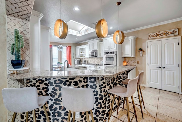 kitchen featuring crown molding, a breakfast bar, appliances with stainless steel finishes, light tile patterned flooring, and white cabinetry