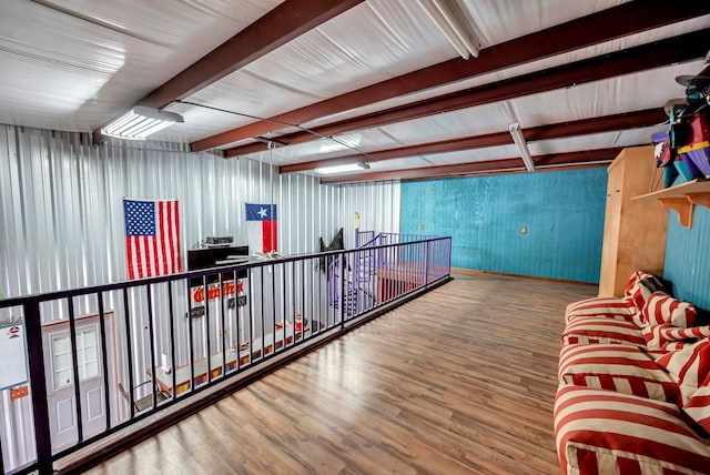 hall with beamed ceiling, wood finished floors, and metal wall