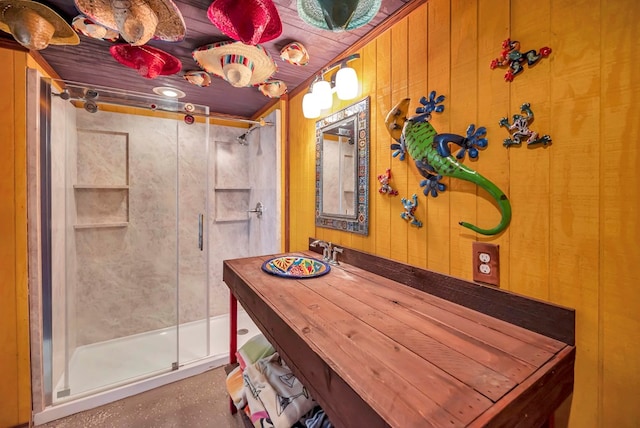 full bathroom featuring a stall shower, vanity, and wood walls