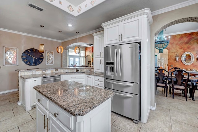 kitchen with arched walkways, appliances with stainless steel finishes, a peninsula, and a sink