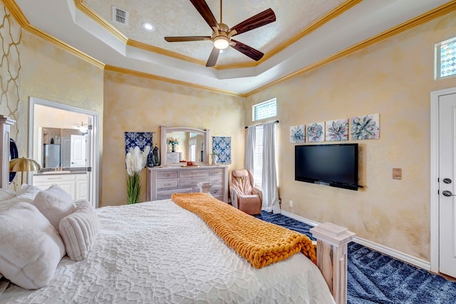 bedroom featuring visible vents, ornamental molding, a ceiling fan, ensuite bathroom, and a raised ceiling