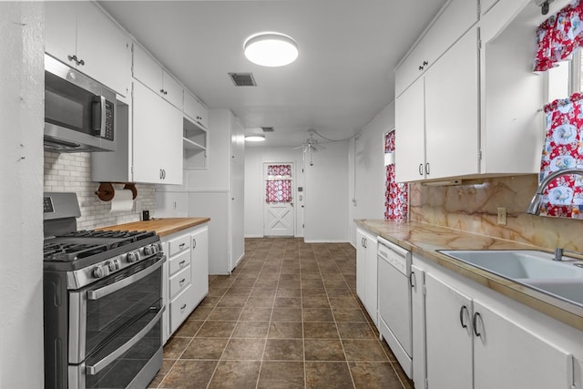 kitchen with white cabinetry, sink, ceiling fan, stainless steel appliances, and decorative backsplash