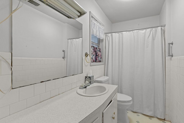 bathroom featuring vanity, toilet, and tile walls